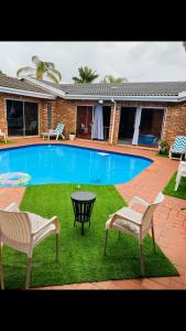 ein Pool mit zwei Stühlen und einem Tisch neben einem Haus in der Unterkunft Comfy Nest Guest House in Durban + 19 Fotos