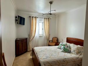 a bedroom with a bed and a chair and a window at Chez Gilbert-Alojamento Local in Alqueidão da Serra
