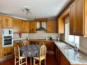 a kitchen with wooden cabinets and a table and chairs at Chez Gilbert-Alojamento Local in Alqueidão da Serra