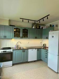a kitchen with blue cabinets and a white refrigerator at Spacious seaside apartment with balcony in Sorreisa