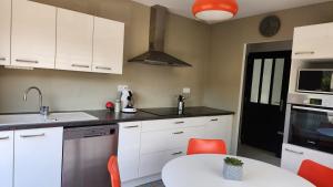 a kitchen with white cabinets and a table with orange chairs at Maison grande terrasse Poligny in Poligny