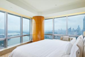 a bedroom with a large white bed and large windows at The Westin Nanjing Xuanwu Lake in Nanjing
