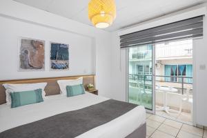 a bedroom with a large bed and a balcony at Larnaca Bay Suites in Larnaca
