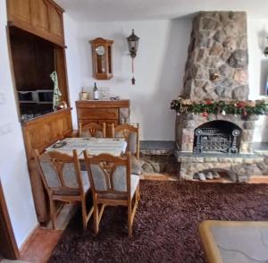 a dining room with a table and a stone fireplace at Jahorina Ski View Apartman in Jahorina
