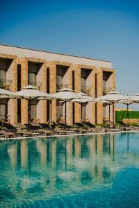 a hotel with a pool with chairs and umbrellas at Blue Inn Hotel in Gökçeada