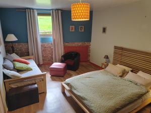 a bedroom with a bed and a chair in it at Les Greniers in Myon