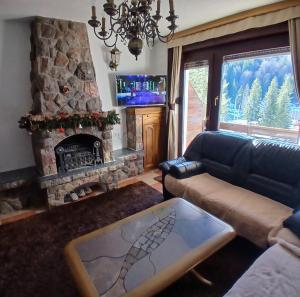 a living room with a couch and a stone fireplace at Jahorina Ski View Apartman in Jahorina