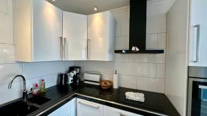 a kitchen with white cabinets and a black counter top at Strandgrün Moderne Ostsee-FeWo am Hansa-Park in Sierksdorf