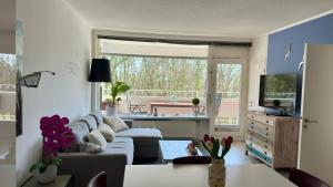 a living room with a couch and a large window at Strandgrün Moderne Ostsee-FeWo am Hansa-Park in Sierksdorf