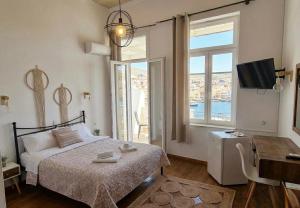 a bedroom with a bed and a desk and a television at Casa di Syrii in Ermoupoli