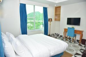 a bedroom with a bed and a desk and a television at Bridge Residency River View Hotel Near Bridge,201 in Muzaffarabad