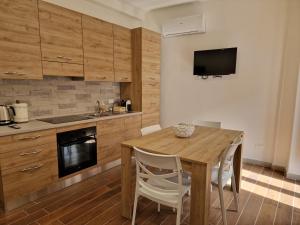 a kitchen with a wooden table with chairs and a television at Dimore Rosantò 2 in Palombaro