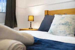 a bedroom with a bed with blue pillows and a lamp at 2-Bedroom Stay with Free Wi-Fi Near Town Centre in Darlington