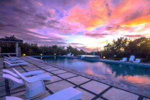 a pool with white lounge chairs and a sunset at Alta Bohol Resort powered by Cocotel in Tagbilaran City