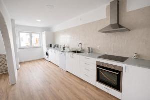 a kitchen with white cabinets and a sink and a stove at Charneca Mar & Sol in Charneca