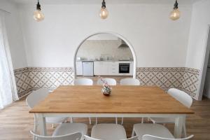 a dining room with a wooden table and white chairs at Charneca Mar & Sol in Charneca