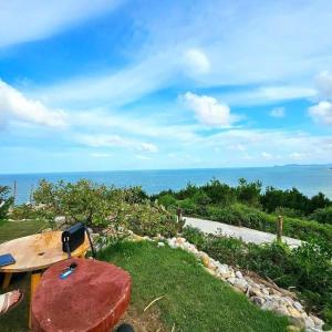 a wooden bench sitting on the grass near the ocean at Đại Việt Hotel in Làng Liễu