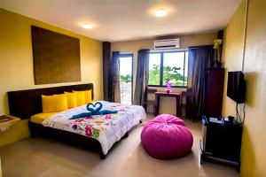 a bedroom with a large bed and a pink ottoman at Alta Bohol Resort powered by Cocotel in Tagbilaran City