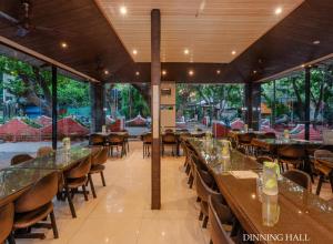 a dining hall with tables and chairs and windows at Blue Park Nature Resort in Mahabaleshwar