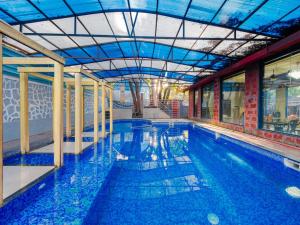 a large swimming pool with blue water in a building at Blue Park Nature Resort in Mahabaleshwar