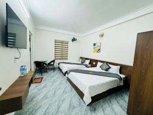 a bedroom with two beds and a flat screen tv at Đại Việt Hotel in Làng Liễu
