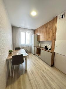 a small kitchen with a table and a refrigerator at Apartment on Satpayeva in Ustʼ-Kamenogorsk