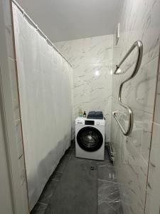 a bathroom with a washing machine in a stall at Apartment on Satpayeva in Ustʼ-Kamenogorsk