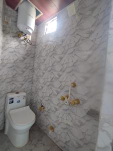 a bathroom with a toilet and a wall with rocks at Nishad Raj bhawan in Vrindāvan