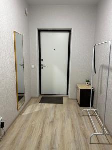 an empty room with a white door and a mirror at Apartment on Satpayeva in Ustʼ-Kamenogorsk