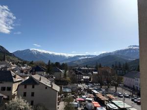 a town with cars parked in a parking lot with mountains at Studio neuf in Barcelonnette