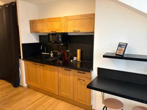 a kitchen with wooden cabinets and a black counter top at Studio neuf in Barcelonnette