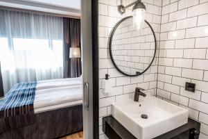 a bathroom with a sink and a mirror and a bed at Scandic Helsinki Airport in Vantaa +31 photos