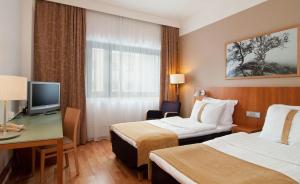 a hotel room with two beds and a desk and a television at Scandic Veromies in Vantaa