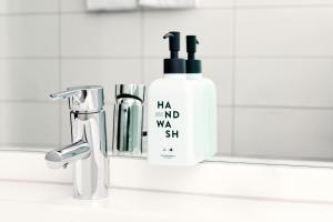 a bathroom sink with a bottle of shampoo next to a mirror at Scandic Veromies in Vantaa