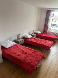 three beds in a room with red blankets and pillows at Chez Bobby in Montréal