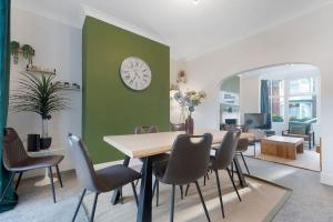 a dining room with a table and chairs and a clock at Spacious 4BR on Leafield Rd in Darlington