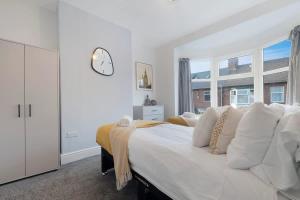 a bedroom with a large bed with a clock on the wall at Spacious 4BR on Leafield Rd in Darlington +43 photos