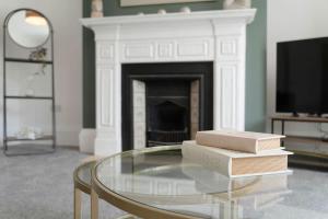 two books on a glass table in a living room with a fireplace at Spacious! 6BR in Beach Road in South Shields
