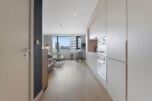 a kitchen with white cabinets and a living room at Stylish Studio With Wi-Fi and Shared Spa Facilities in Manchester