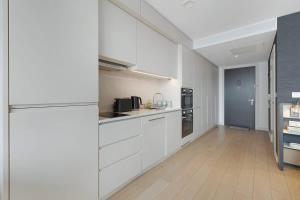 a large kitchen with white cabinets and a wooden floor at Stylish Studio With Wi-Fi and Shared Spa Facilities in Manchester