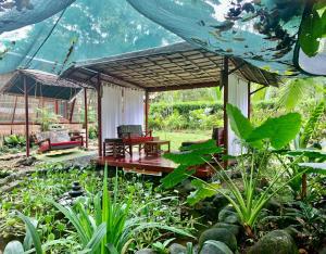a pavilion with a table and chairs in a garden at Uva Blue Villas - Zen Villa 1 - 3 Bedroom Villa, Private Garden & Yoga Deck in Puerto Viejo