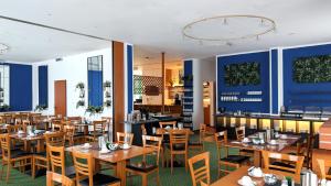 a restaurant with wooden tables and chairs and blue walls at ACRON Hotel Wittenberg in Lutherstadt Wittenberg