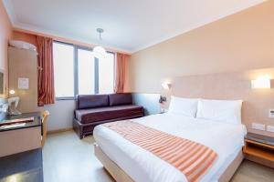 a hotel room with a large bed and a chair at Eurotraveller Hotel - Premier - Harrow in Harrow