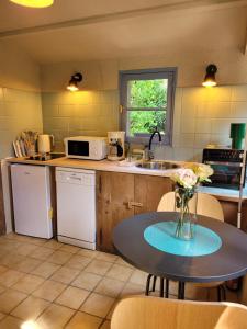 a kitchen with a table with a vase of flowers on it at Domaine Bel Air 855 - Gîte Belle in Saint-Denis-de-Villenette