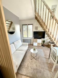 a living room with a couch and a tv at Maison individuelle Hourtin centre jardin clos in Hourtin