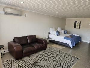 ein Schlafzimmer mit einem Bett und einer Ledercouch in der Unterkunft Clanwilliam Accommodation in Clanwilliam
