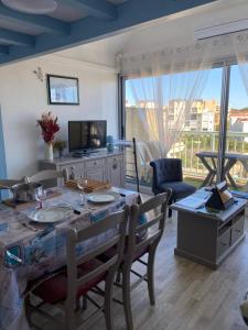 a dining room with a table and a television at Pause Soleil in Gruissan