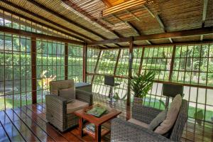 a screened in porch with chairs and a table at Uva Blue Villas - Zen Villa 1 - 3 Bedroom Villa, Private Garden & Yoga Deck in Puerto Viejo