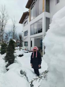 a woman standing in the snow in front of a house at Hotel Pahalgam Villas in Pahalgām