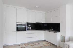 a white kitchen with white cabinets and a microwave at Apartman Dijamant in Sarajevo